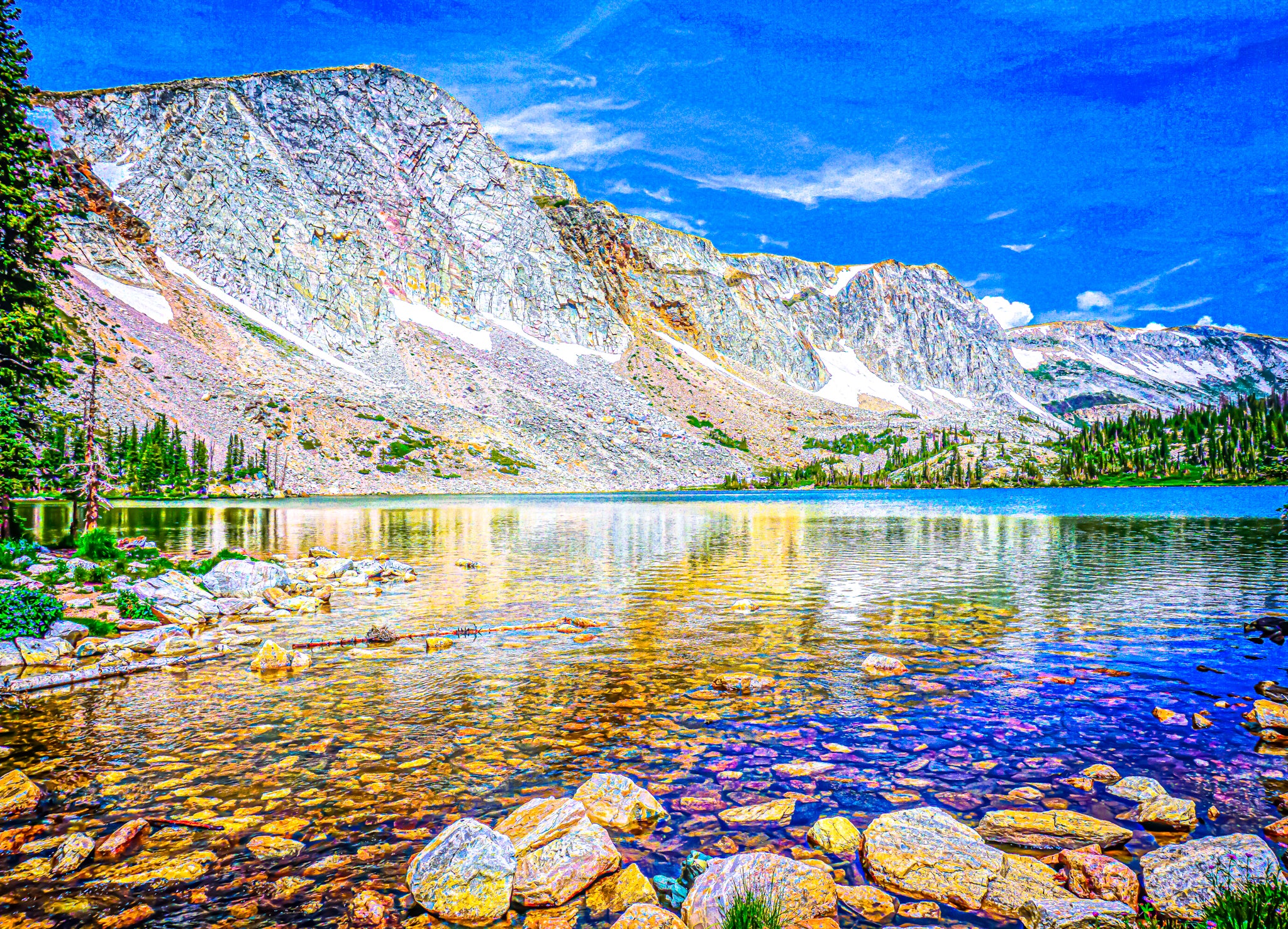 This image shows the transparency of Mirror Lake in Medicine Bow National Forest by dissecting the horizon of a water line from the massive sedimentary wall. The bright summer colors shine through in bold and subtle places like in the lake or amidst the rock faces. Lastly, the granular dimension of in the image portrays a post-impressionist style of dot-painting known as Pointillism (Link: https://artincontext.org/pointillism/).