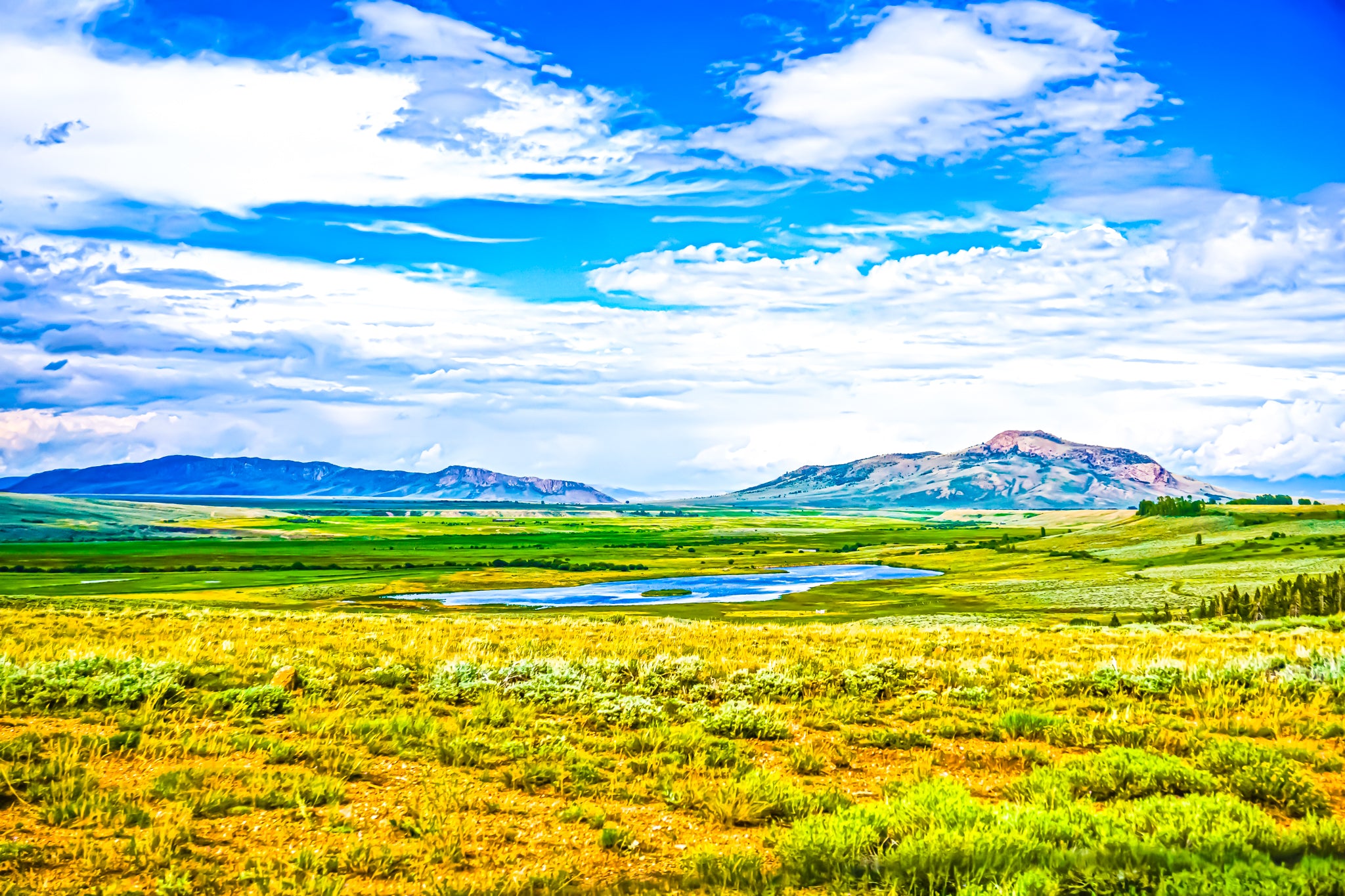This photograph give definition to the motto, "Colorful Colorado," depicting a mixture of flat and elevated terrain that is very spacious. This photograph captures nearly 20 miles in foreseeable distance and features a natural lake in a small and deep basin.